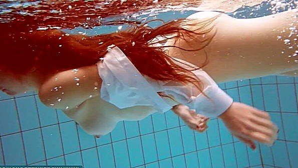 Рыжая барышня плавает и оголяется под водой